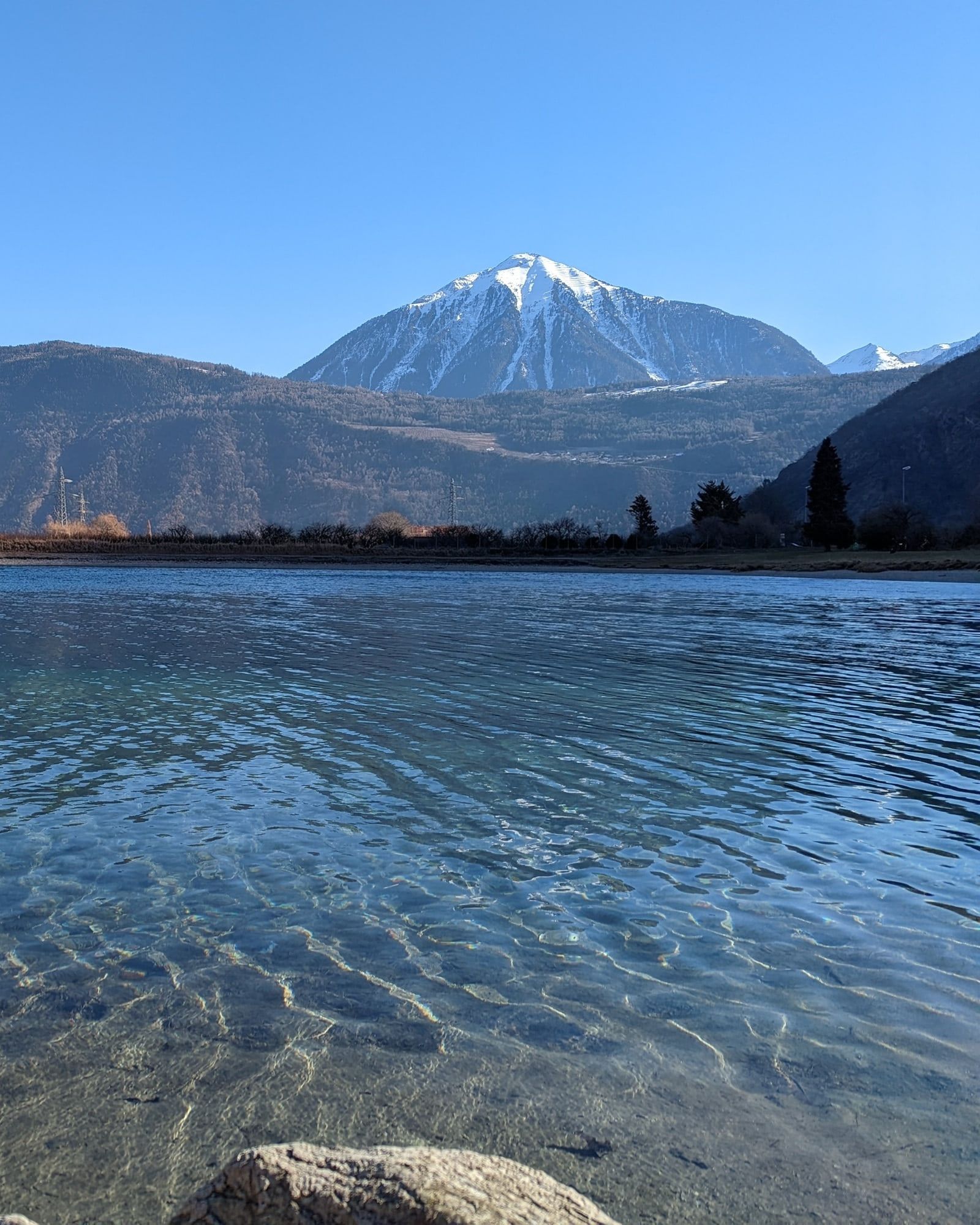 The clear water of Lac du Rosel, below snow-capped mountains.
